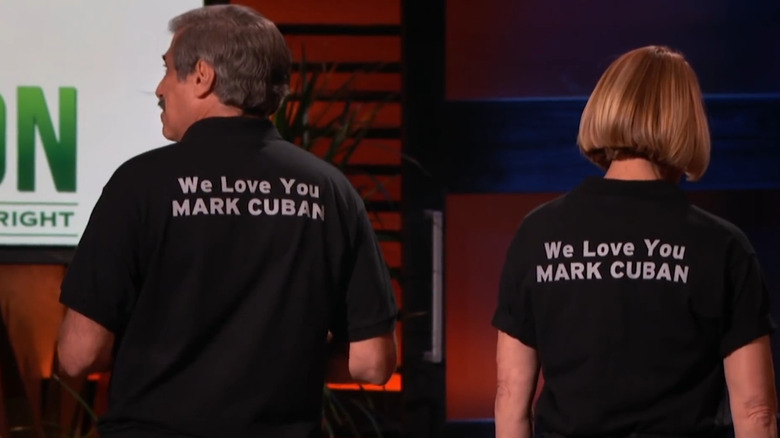 Don Lessem and Val Jones show the back of their shirts, which say, We Love You MARK CUBAN