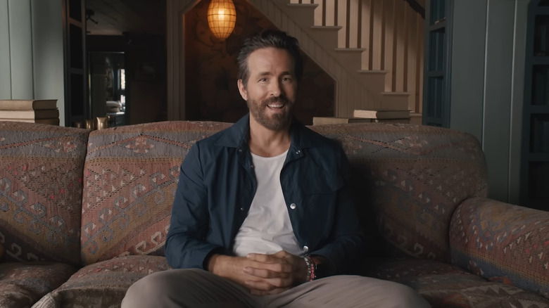 Ryan Reynolds sitting on couch and smiling