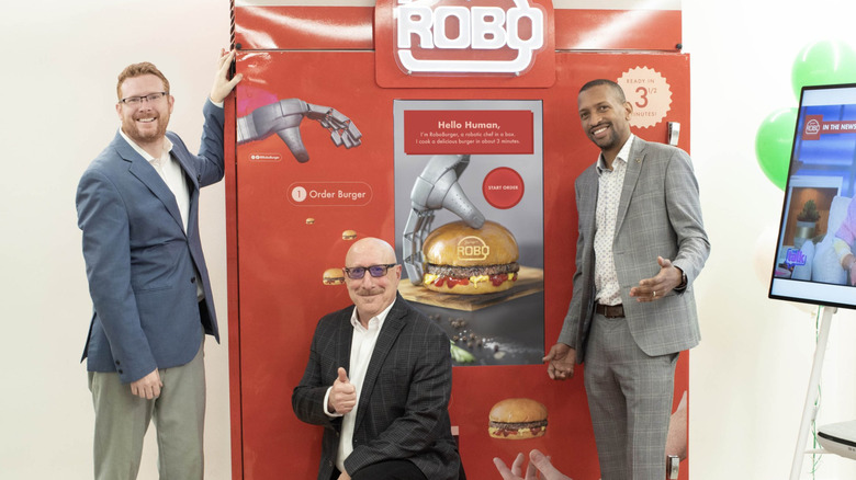 Braido, Siegel, and Wilson posing for the camera while in front of their RoboBurger machine