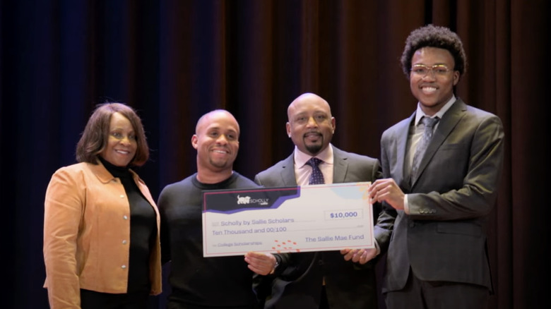 Christopher Gray and Daymond John joined onstage by Sallie Mae Chief Donna Vieira while presenting a scholarship to a student