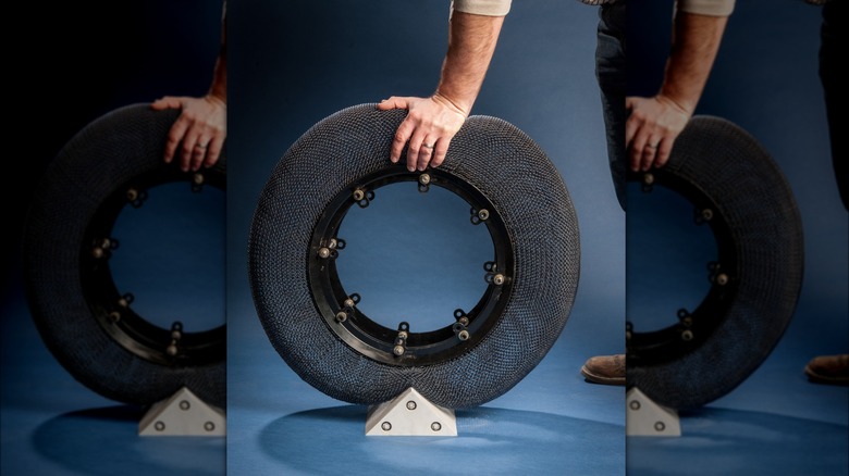 A man's hand pressing down on a NiTinol mesh tire sitting on a wedge