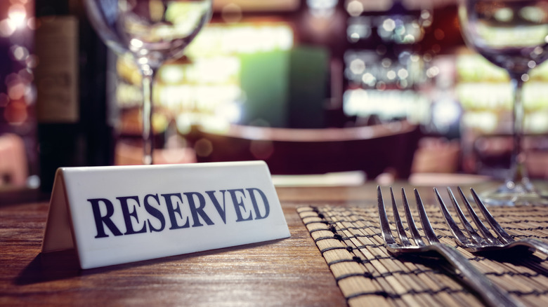 Reserved sign on table next to wine glasses and forks