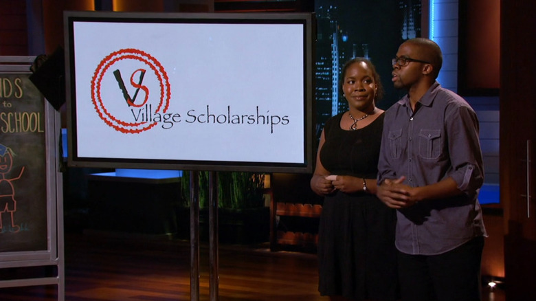 Antonio and Tasha presenting next to Village Scholarships display