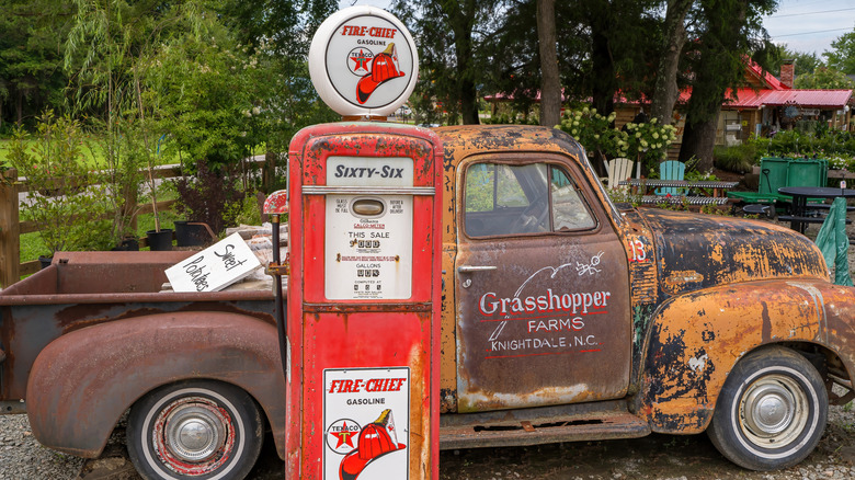 Rusty truck next to antique gas pump