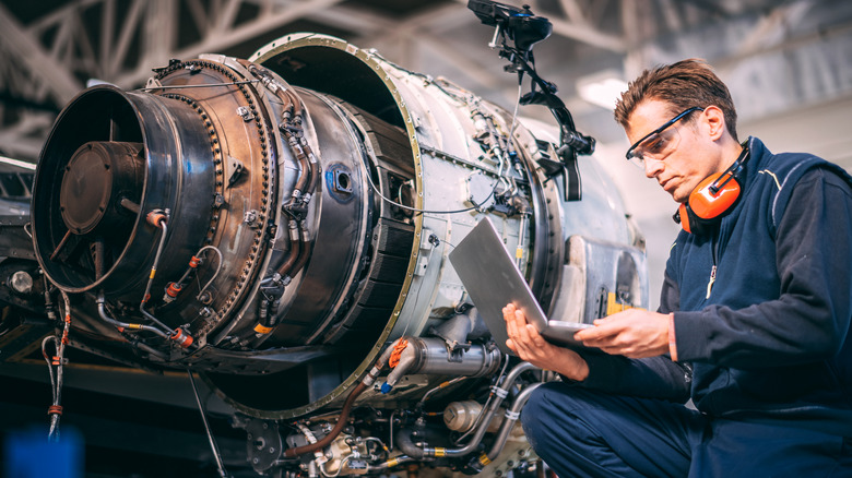 A mechanic inspecting an airplane engine