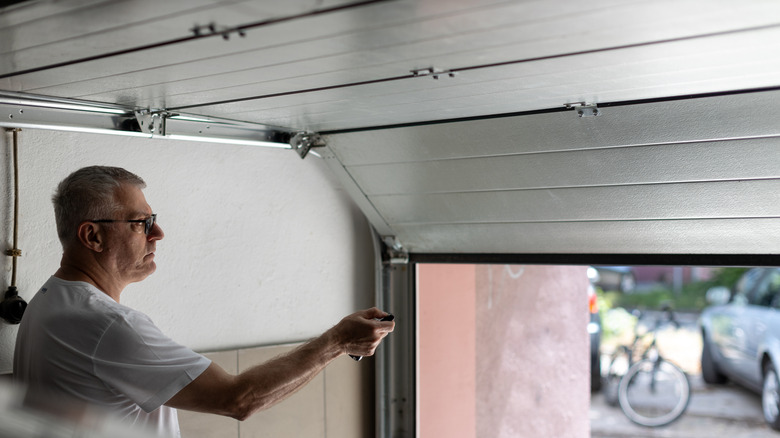 man pressing button on garage door remote