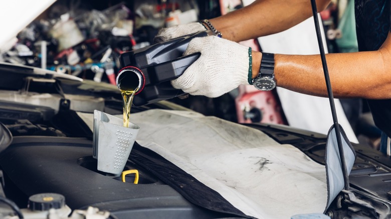 A mechanic pouring engine oil into a car's engine