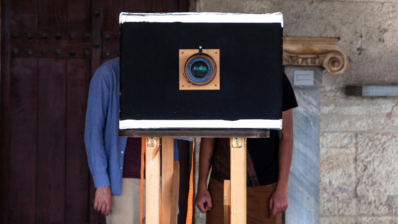 People looking through a reproduction of a camera obscura at the museum of the Agora in Athens.