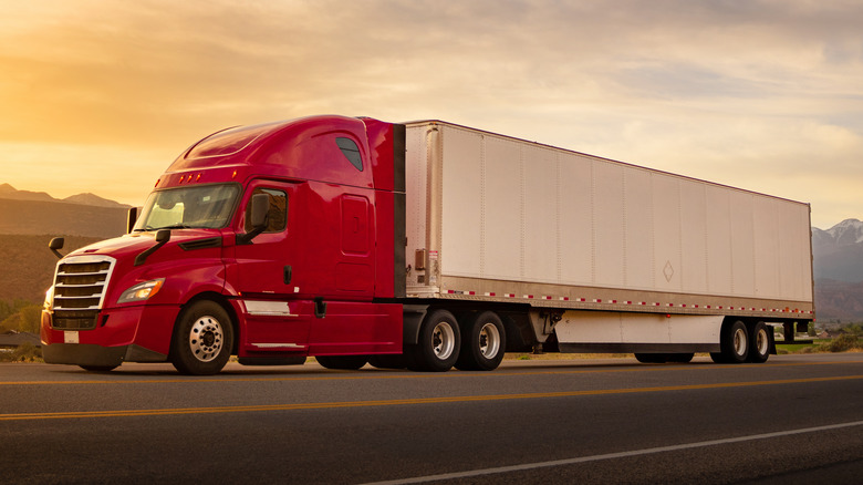 A red and white semi-truck driving on a highway