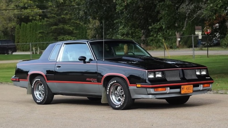 1983 Oldsmobile Hurst/Olds parked on the roadside with trees in the background