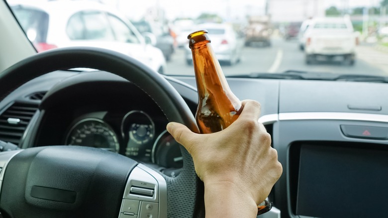 Driver behind the wheel with a clear bottle