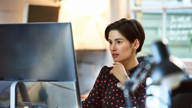 Una mujer trabaja en un monitor de escritorio.