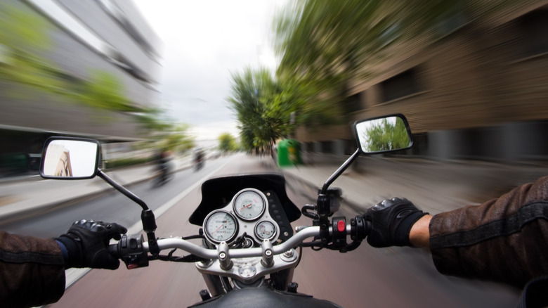 Point of view from a motorcycle rider on a city street at high-speed with blurred surroundings