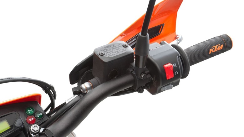 A red kill switch on an orange and black motorcycle handle with a KTM logo on the throttle