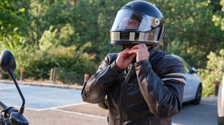 Motorcycle rider fastens helmet