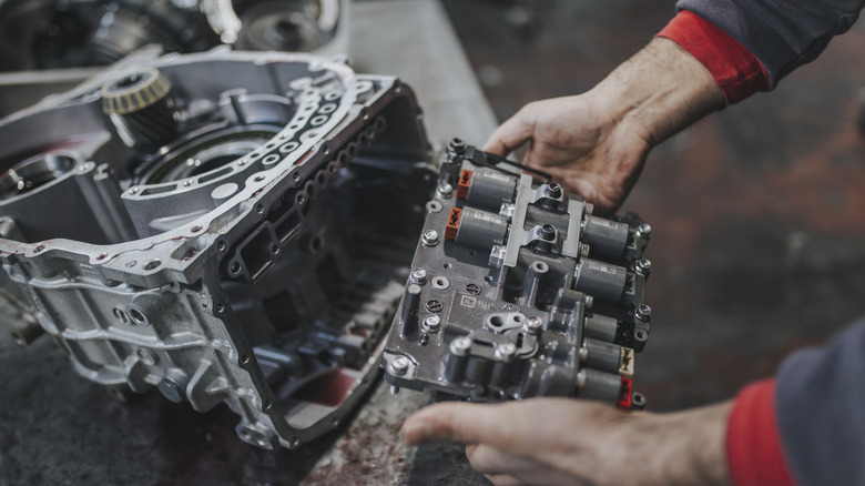 A mechanic's hands hold transmission valves