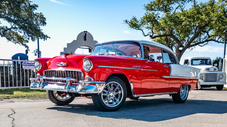 Red 1955 Chevy Bel Air parked under trees on a sunny day