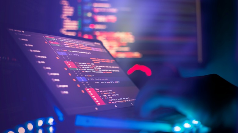 Computer screen with code and hands typing