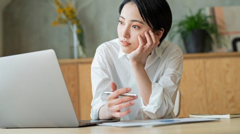 Woman thinking with a laptop