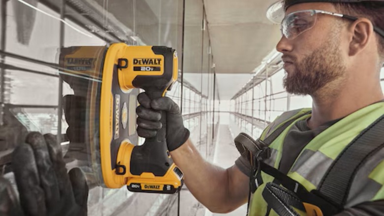 A glass installer using a DeWalt Grabo Lifter to hold a pane of glass.