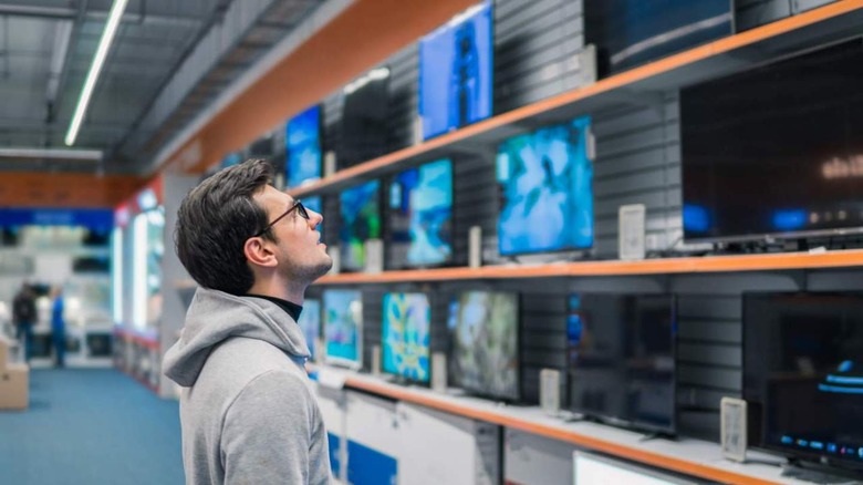 man looking at new TVs