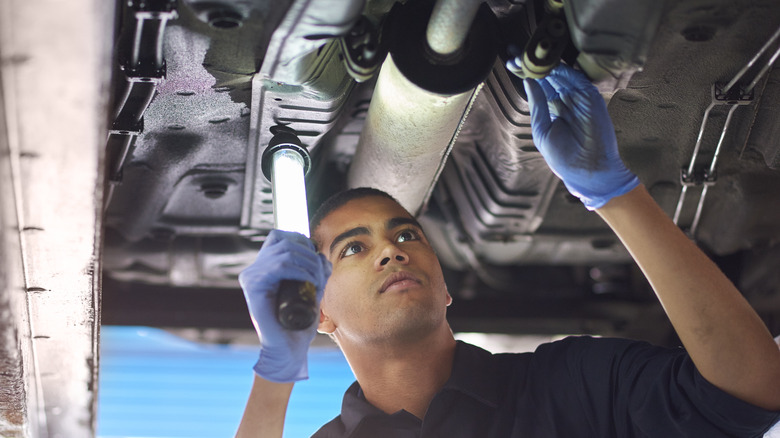 Mechanic inspecting underside of car