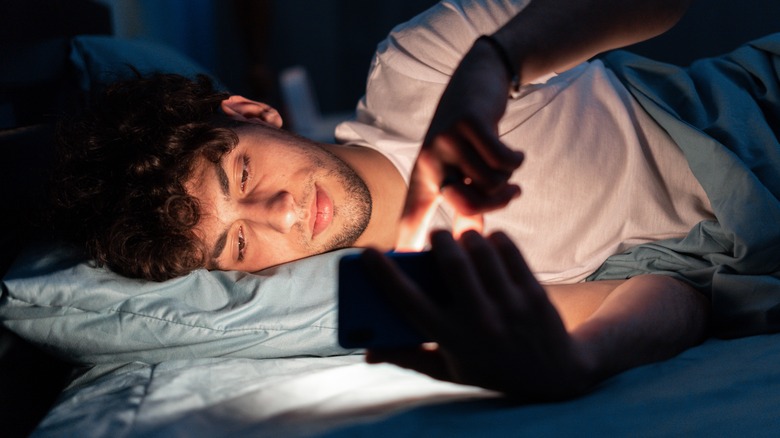 Young man on his phone while in bed