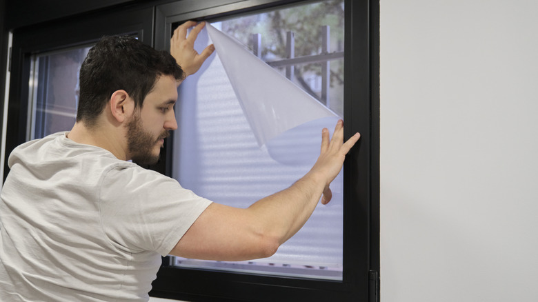 man installing frosted window vinyl on window glass