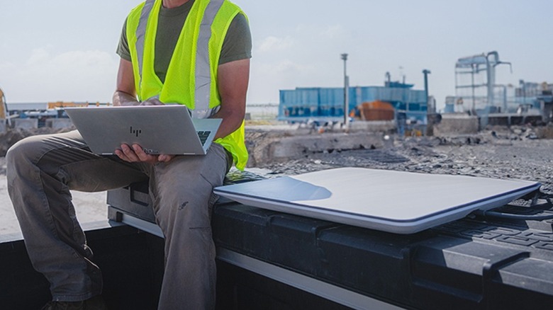 Construction worker sitting next to a Flat High Performance Starlink dish using his laptop