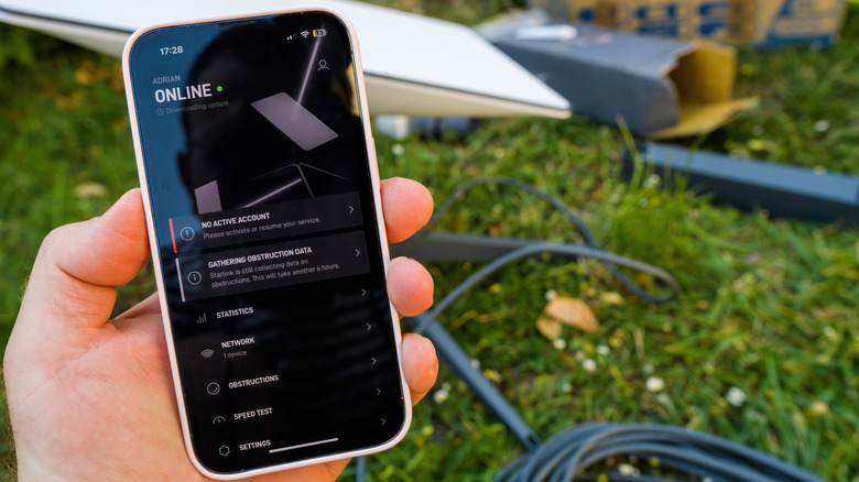 Person holding a phone with Starlink app open, showing the satellite in the background is online.