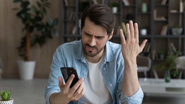 Visibly upset and confused man holding a phone