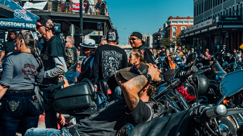 man rests on motorcycle in the middle of a biker's rally