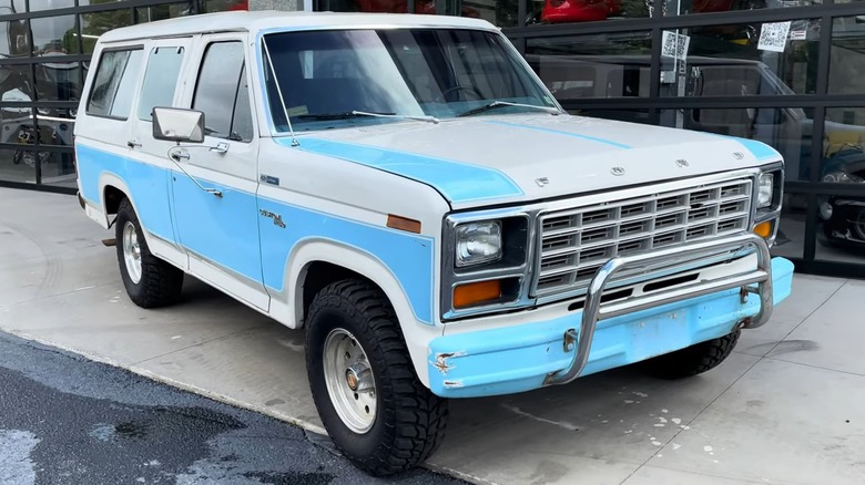 A blue and white 1981 Ford B-150 parked on pavement.