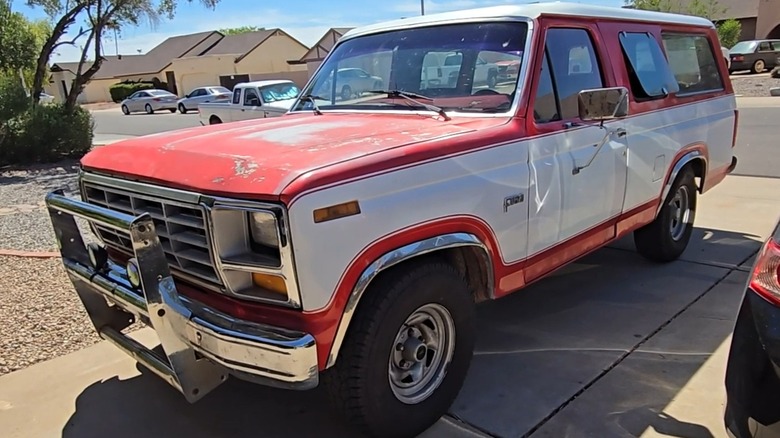 A red and white 1982 Ford B-150 parked outside.