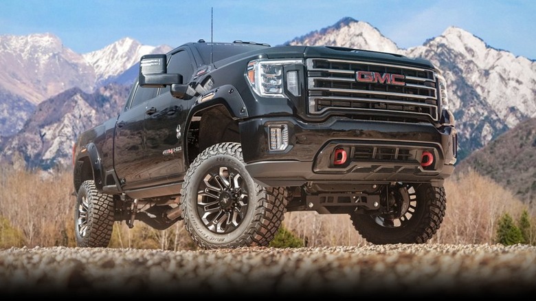 Front view of a looming black GMC 2500HD truck on gravel.