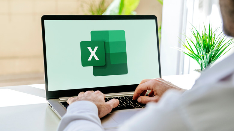 Man working on a laptop showing Excel logo