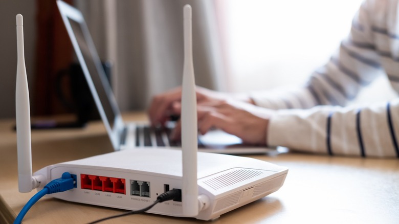 white router with woman in background typing on laptop