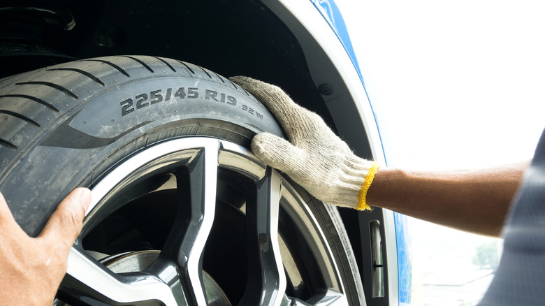 Man with glove inspecting tire sidewall