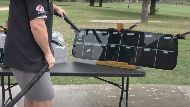 A man testing 28 windshield treatment products with air and water hoses