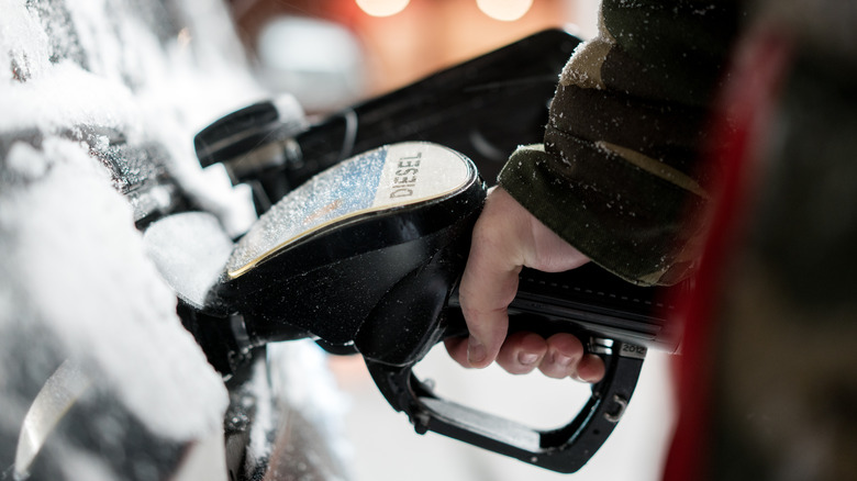 Person fueling snowy car