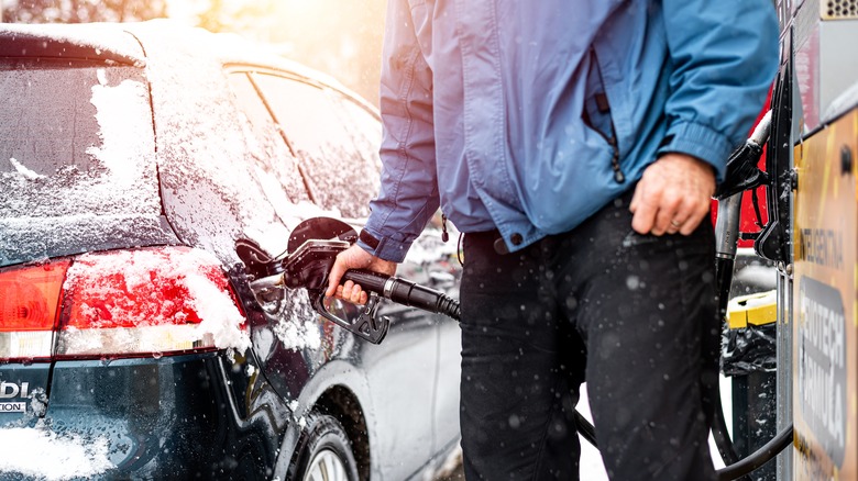 Person fueling snowy car