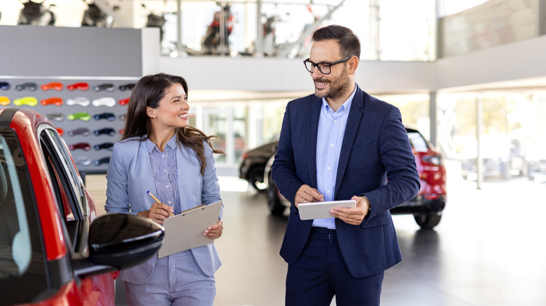 A male buyer discussing matters with a female dealership agent about a car on display