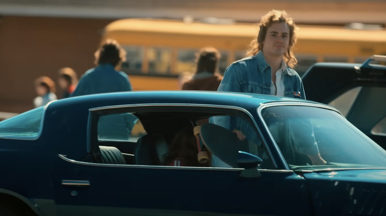 A scene showing Billy entering his blue coupe after fetching his sister Max from school