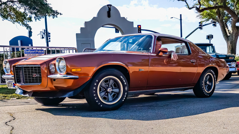 A metallic orange 1970 Chevrolet Camaro Z/28 being driven to an auto show