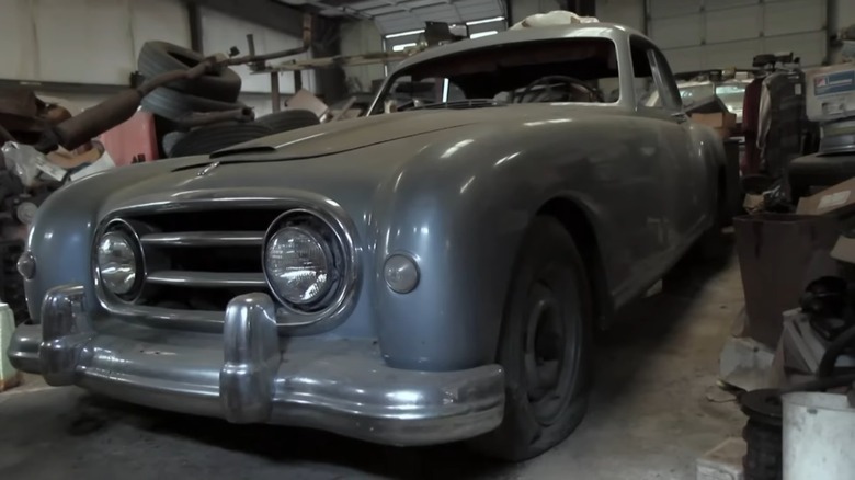 A gray Nash-Healey parked in a garage.