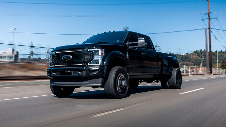 Black Ford F-450 truck driving down the road on a sunny day