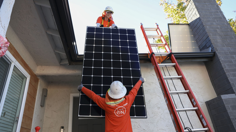 Workers installing solar panels on a home