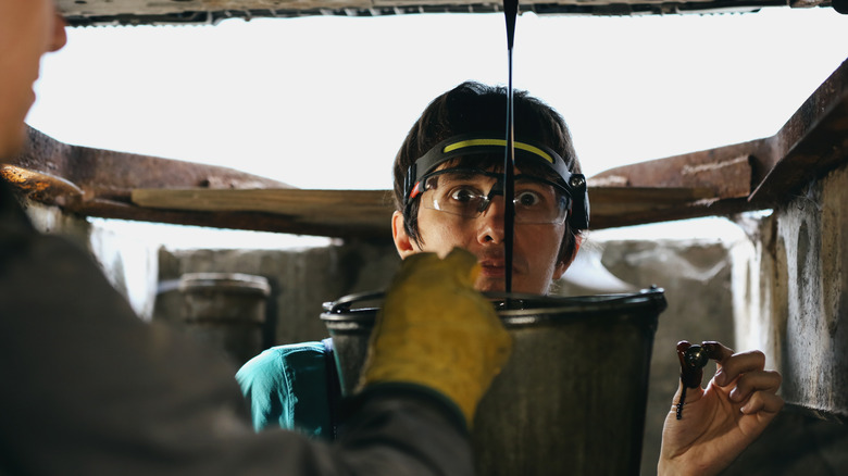 Mechanic watching oil being drained from a car sump