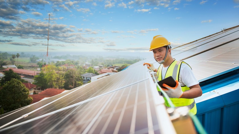 Person inspecting rooftop solar panel