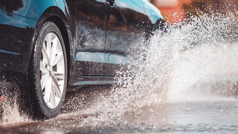 Close-up of a car driving through a puddle